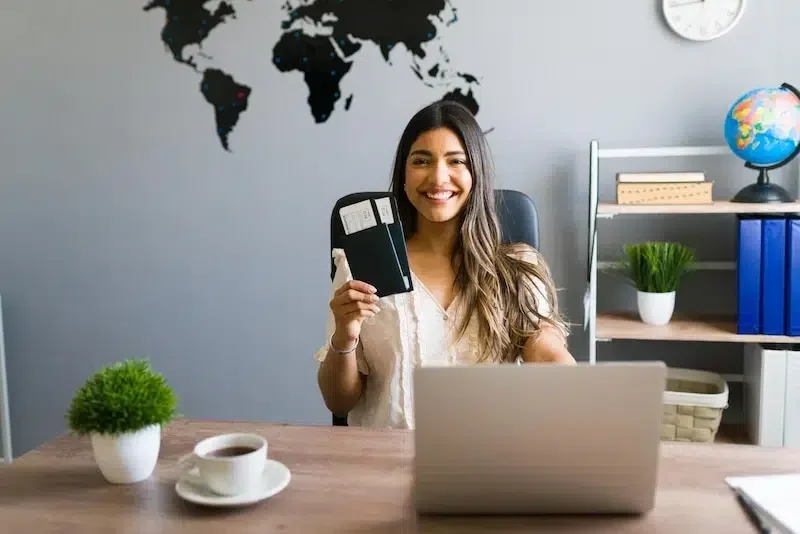 Smiling consultant holding a passport and flight tickets at a desk for a training visa application with PACE Migration.