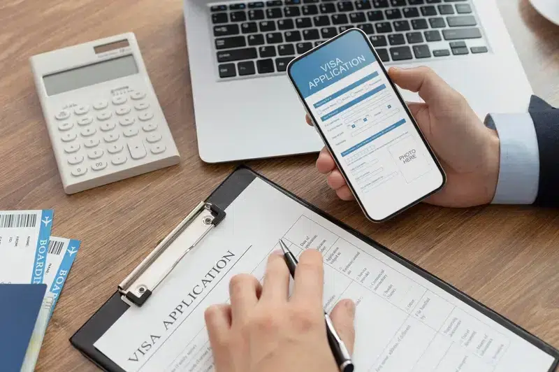 Calculator, visa application form, and boarding passes on a desk at Pace Migration & Education Consultancy, Sydney migration agents.
